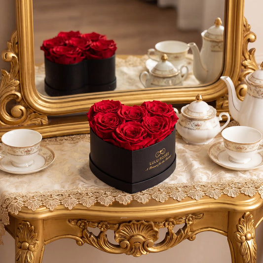 LULU ROSÉE baby heart box red roses black classic box displayed on on a decorative table with teacups and a mirror in the background