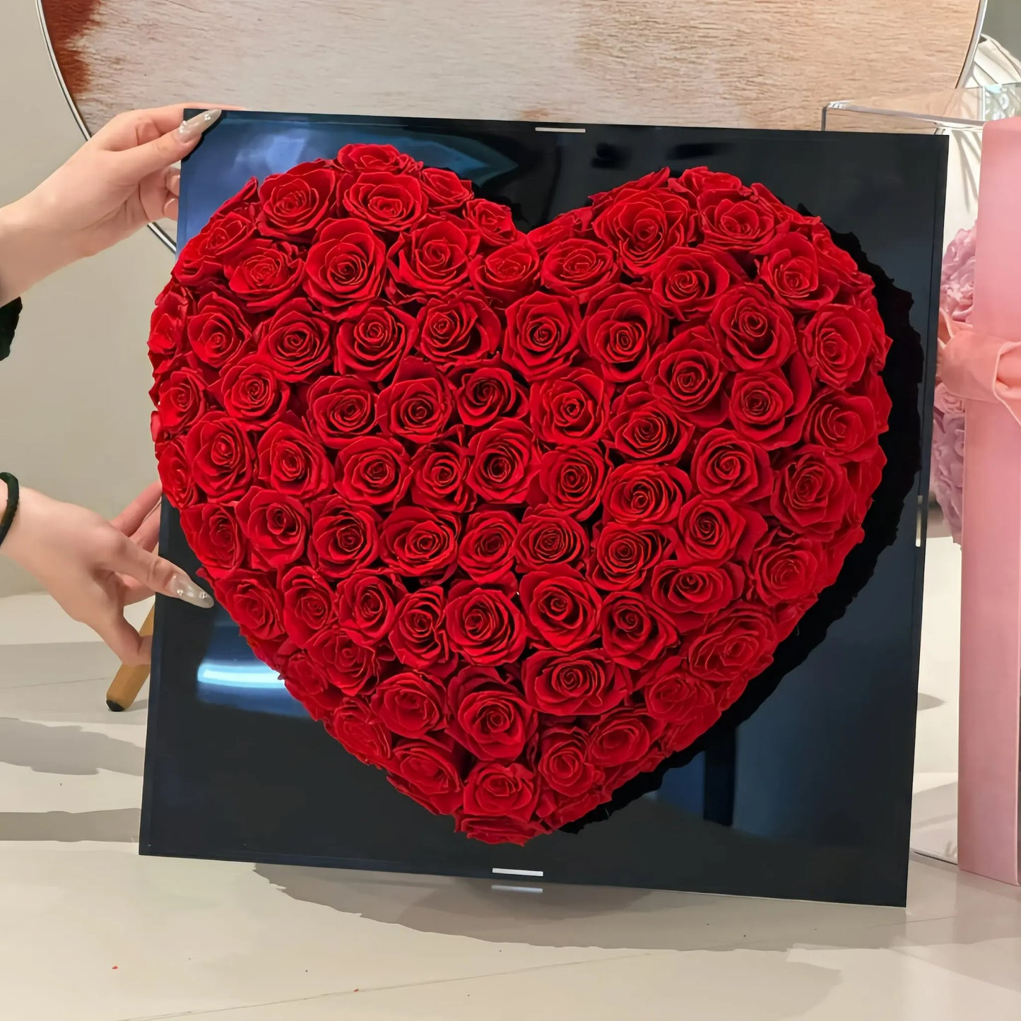 LULU ROSÉE 99 3D heart rose box red roses in a black box held by a person.