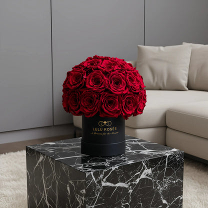LULU ROSÉE classic superdome box red roses black classic box on a marble side table in a living room.