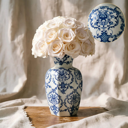 LULU ROSÉE large blue porcelain vase white rose on a wooden surface with a soft fabric background.
