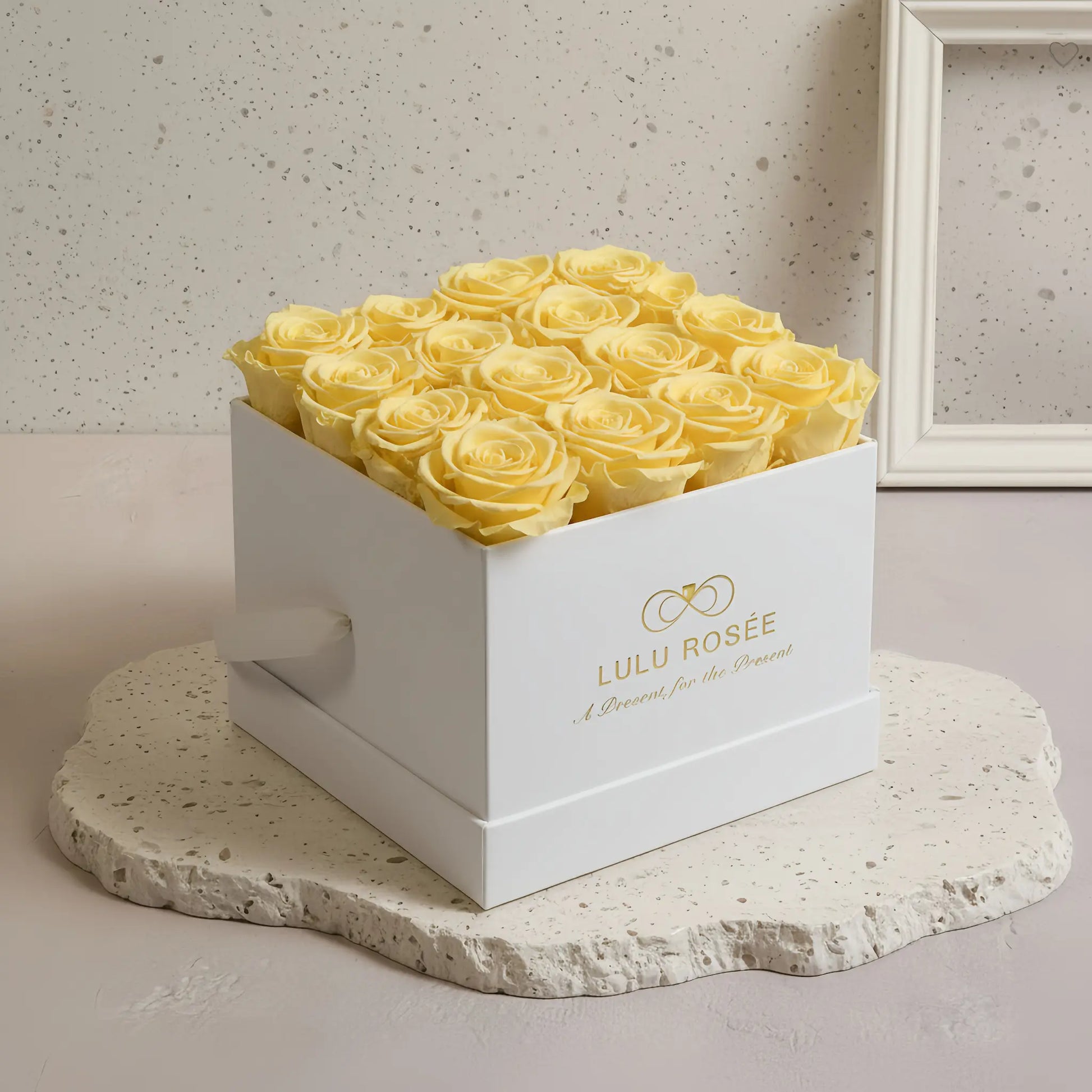 LULU ROSÉE medium square box light yellow roses white classic box on a stone surface with a neutral background
