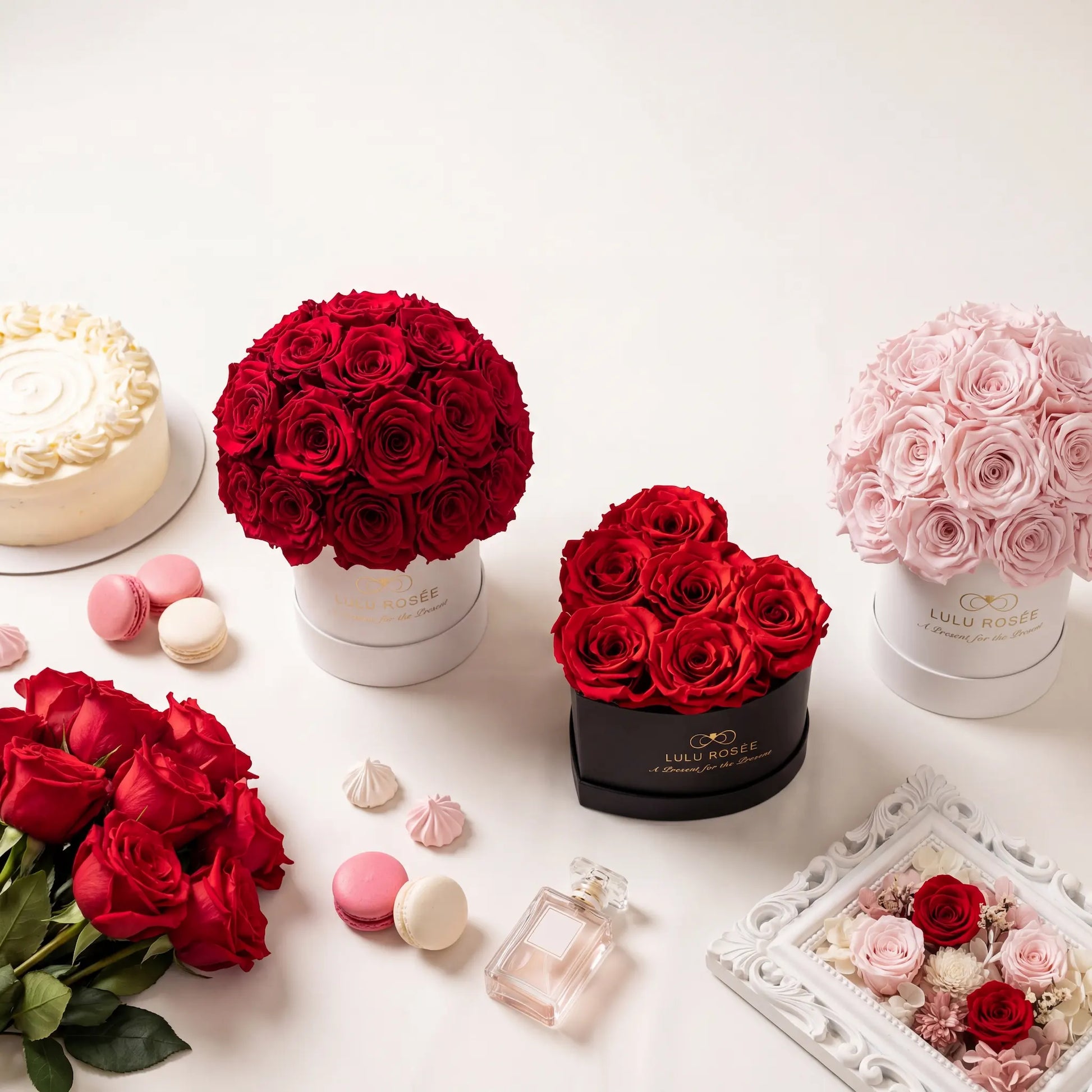 A collection of LULU ROSÉE preserved rose boxes including heart box, round box, and dome box arranged on a wedding gift table
