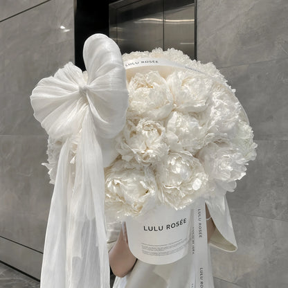 LULU ROSÉE Moonlight Peony Round Box lifestyle photo, large tulle bow white preserved peony box in modern elevator scene, quiet luxury home decoration
