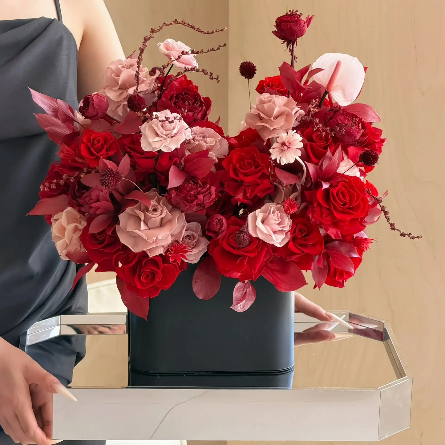 LULU ROSÉE Romantic Red Parisian Bloom Garden Preserved Flower Arrangement in a black vase on a reflective surface with a neutral background