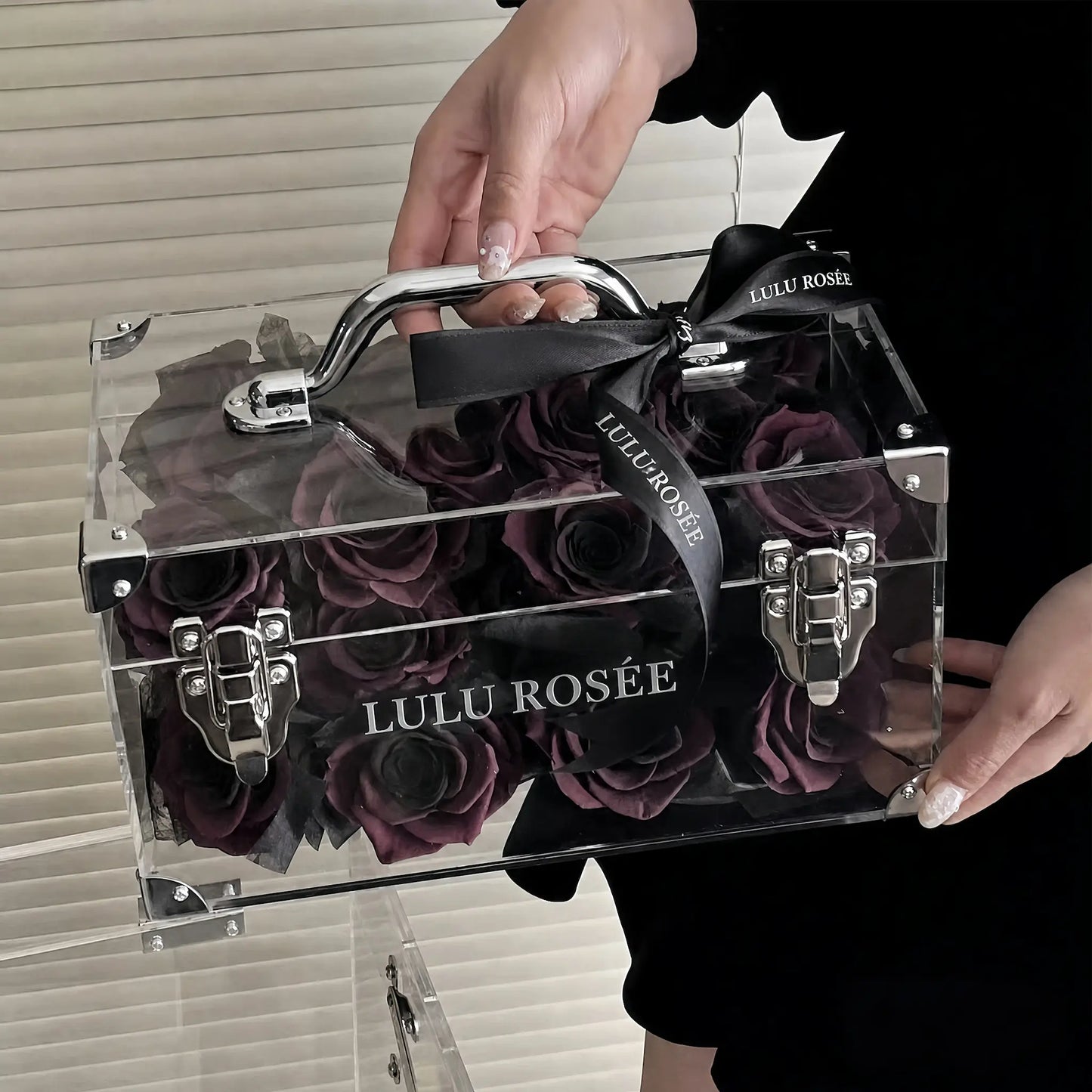 LULU ROSÉE Petite Eternal Acrylic Handbag Rose Box, small transparent acrylic handbag-shaped gift box filled with solid dark purple preserved roses dark tabletop handheld shot, customizable flower color options, mini luxury everlasting floral souvenir for birthday, anniversary & romantic gift giving